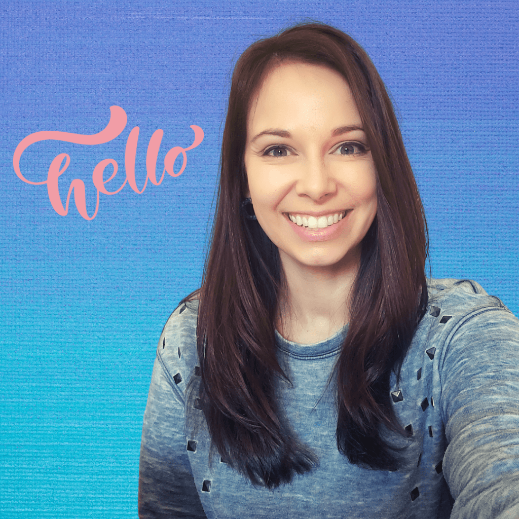 Picture of me, Andrea, a mid-30s brunette, smiling at the camera in greeting. I'm in a grey sweatshirt with metal studs. The word "hello" appears over my shoulder in a swirling pink font.
